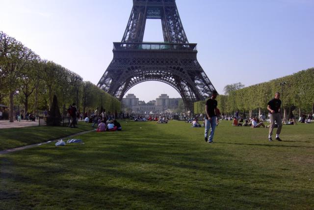 People hanging out and playing soccer in front of the Eiffel Tower.