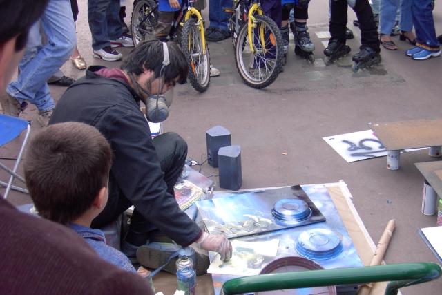 Street artist painting with spray paint and pie tins